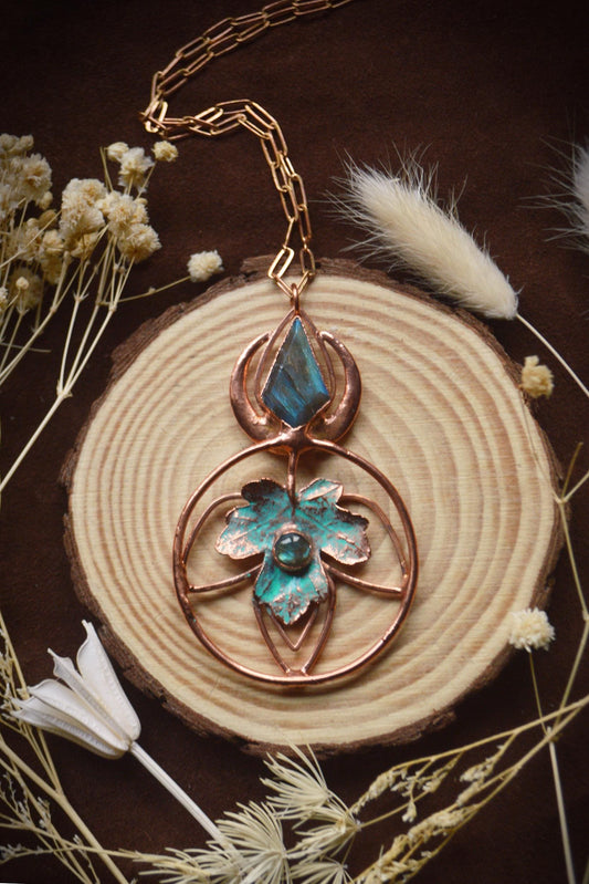 May include: A copper wire necklace with a pendant featuring a blue labradorite stone and a copper leaf design.